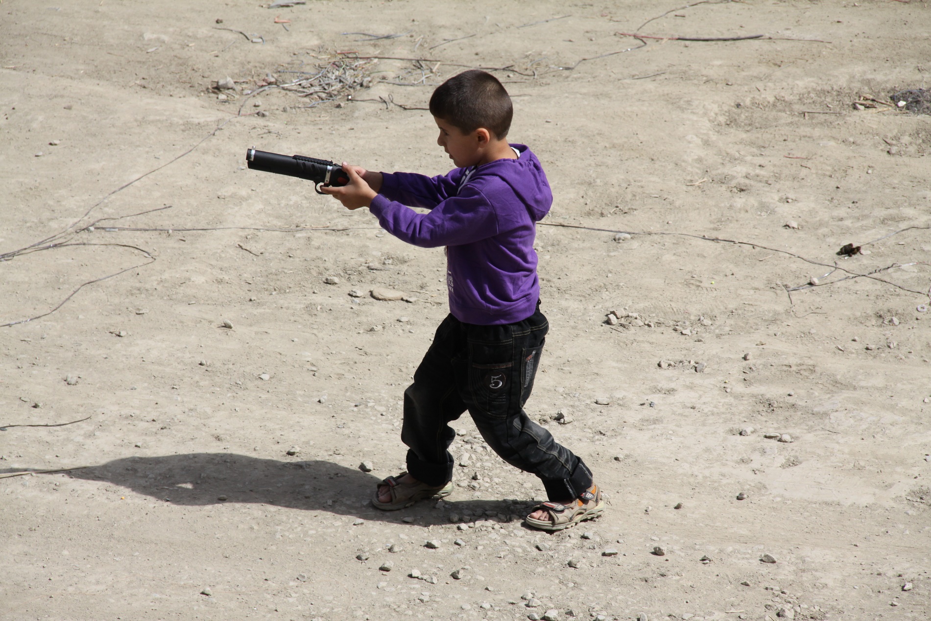 Jovem brinca com um arma de brinquedo no Afeganistão. Acabar com a banalização da violência é dos grandes desafios dos Objetivos do Desenvolvimento Sustentável (ODS)