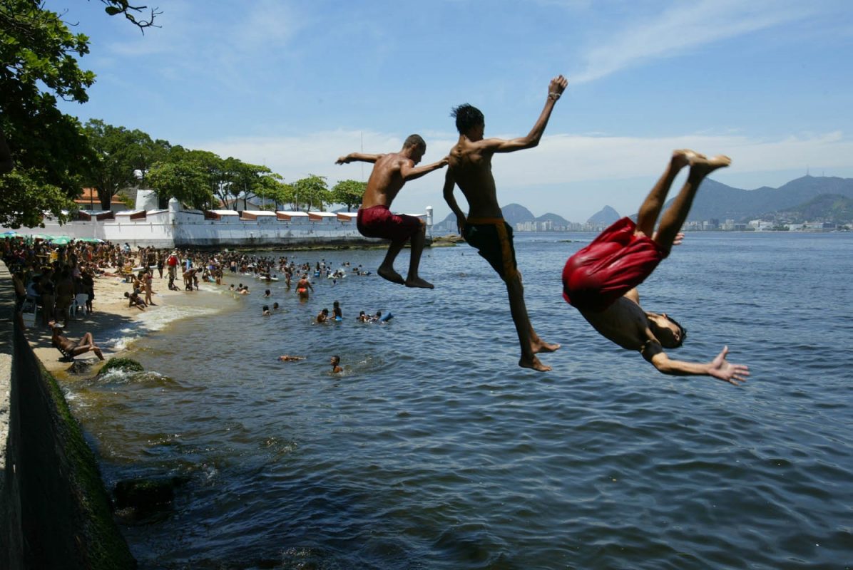 Jovens mergulham na poluída praia do Gragoatá, em Niterói. Doenças de veiculação hídrica provocam atraso escolar de dois anos. Foto Custódio Coimbra