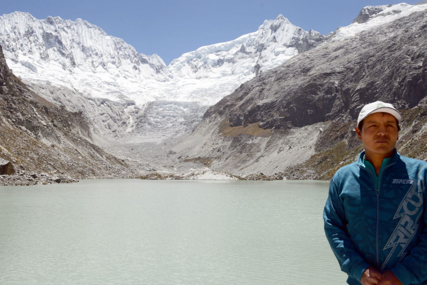Saul Luciano em frente ao lado e ao pico ameaçados pelas mudanças climáticas