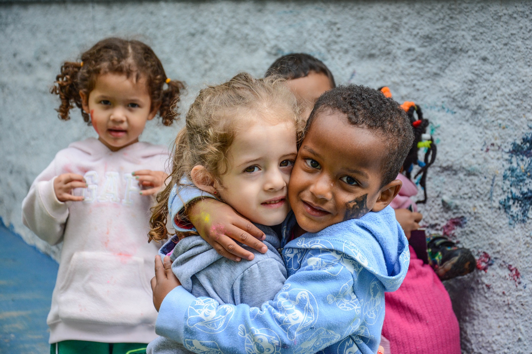 Crianças se abraçam durante uma ação com voluntários de empresas organizada pelo Atados em uma creche de São Paulo