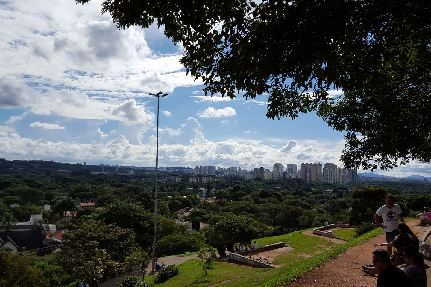 A praça do Pôr do Sol, no Alto de Pinheiros, ocupada com grupos de pessoas sentadas na grama ou em cadeiras de praia