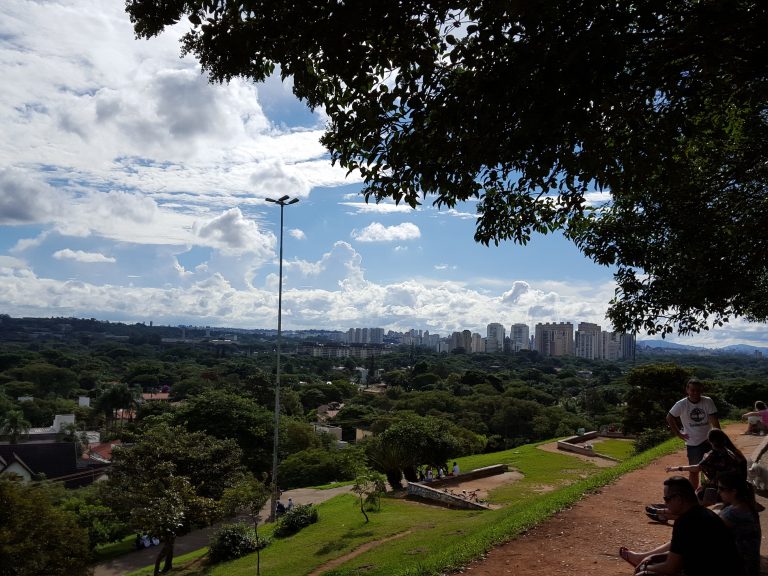 A praça do Pôr do Sol, no Alto de Pinheiros, ocupada com grupos de pessoas sentadas na grama ou em cadeiras de praia