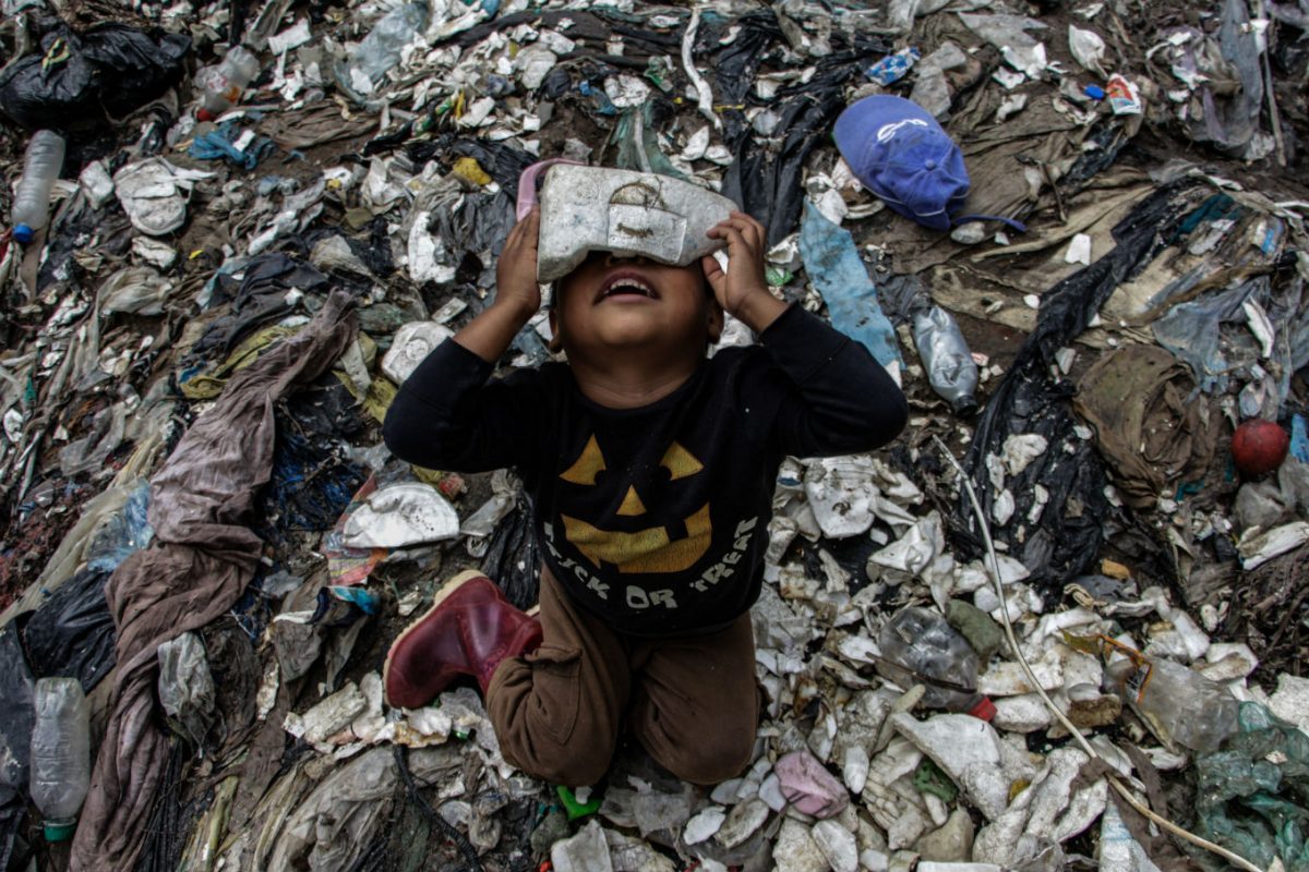 Menino brincando no lixo. Foto de Josue Decavele/ Anadolu Agency/ AFP