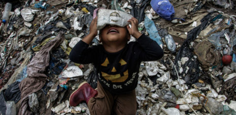 Menino brincando no lixo. Foto de Josue Decavele/ Anadolu Agency/ AFP