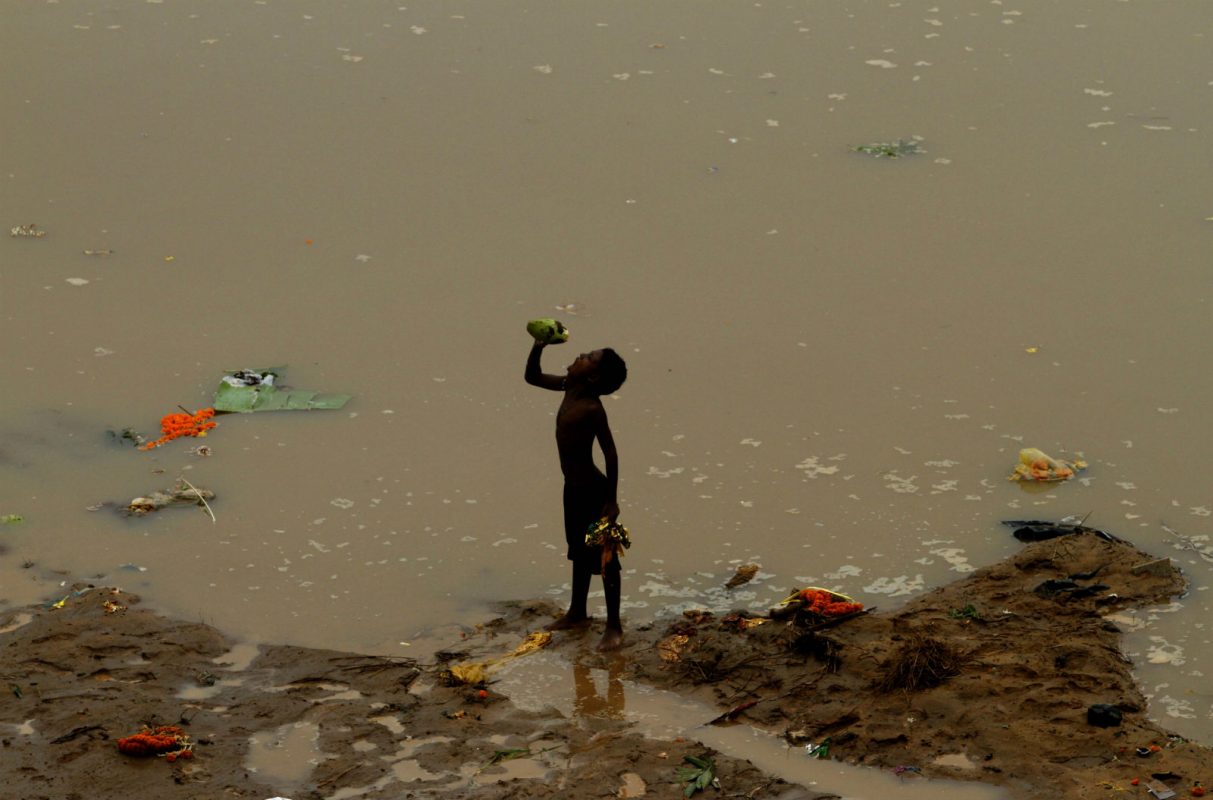 Menino bebendo resto de água de coco, kuakhai, na Índia. Foto de Biswaranjan Rout/NurPhoto/AFP