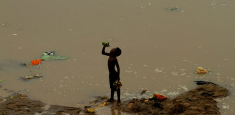 Menino bebendo resto de água de coco, kuakhai, na Índia. Foto de Biswaranjan Rout/NurPhoto/AFP