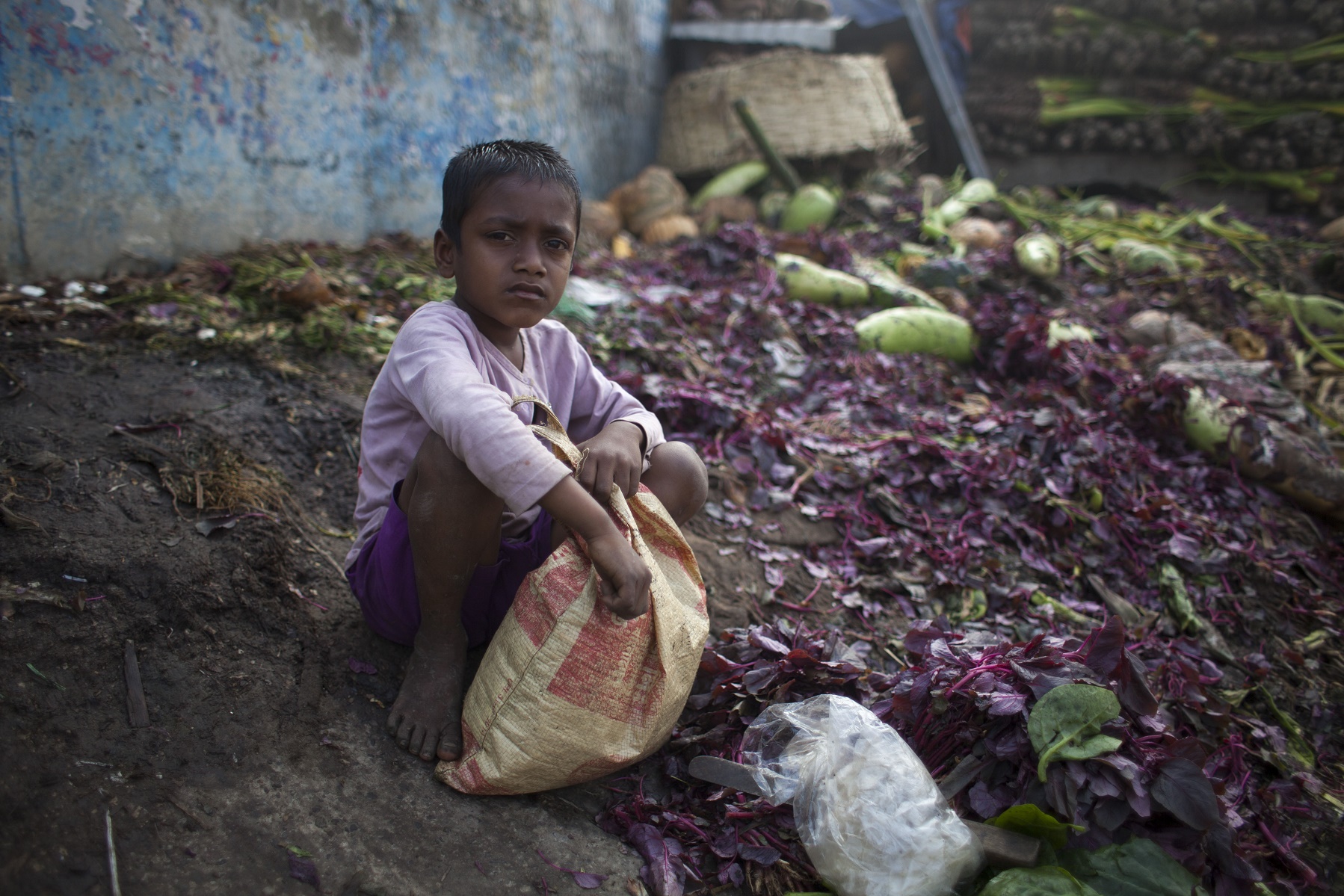 Menino recolhe vegetais num lixão em Bangladesh. Foto de Zakir Hossain Chowdhury/NurPhoto