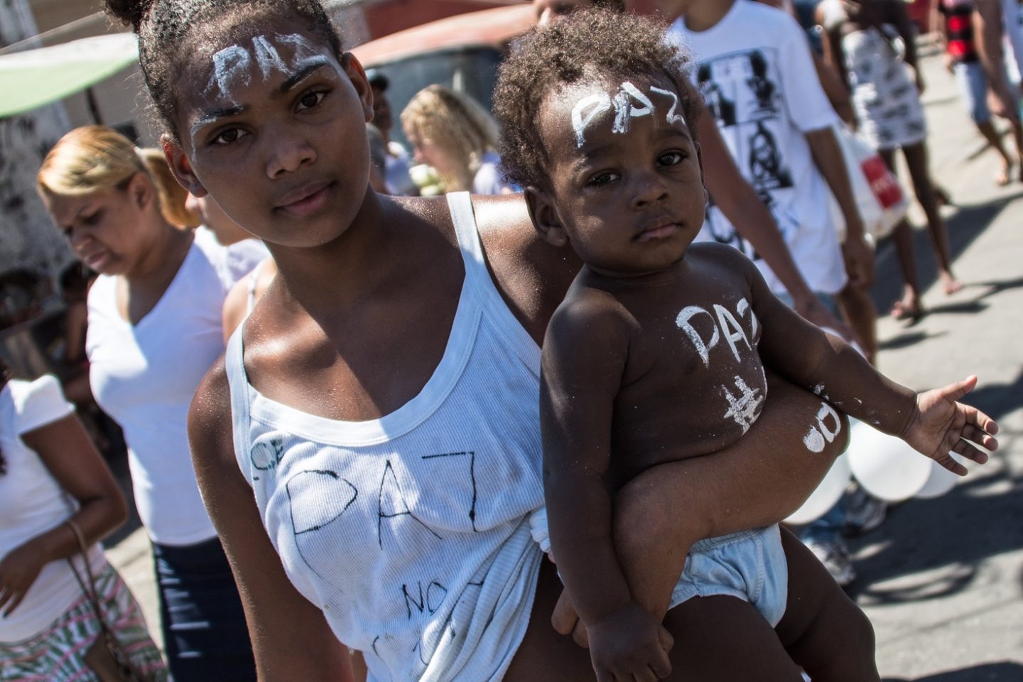Moradora do Compelxo do Alemão carrega o filho durante a marcha pela paz no Rio de Janeiro. Foto de Christophe Simon/AFP
