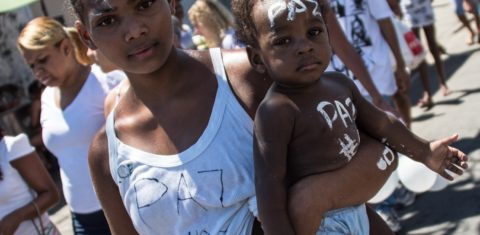 Moradora do Compelxo do Alemão carrega o filho durante a marcha pela paz no Rio de Janeiro. Foto de Christophe Simon/AFP
