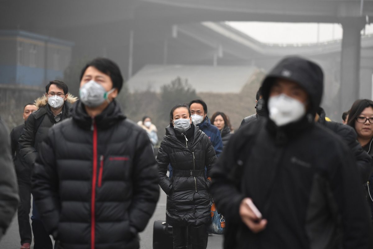 Moradores de Pequim usam máscaras para se proteger da poluição rotineira causada pelos combustíveis fósseis. Foto Greg Baker/AFP