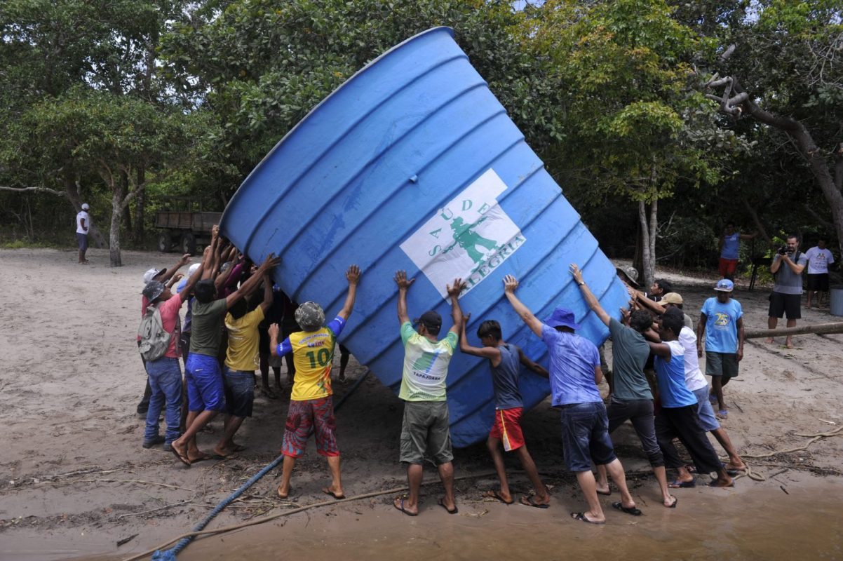 Ribeirinhos da comunidade de Anumã, no Tapajós, carregam caixa d'agua comunitária (Foto Chico Ferreira/Divulgação)
