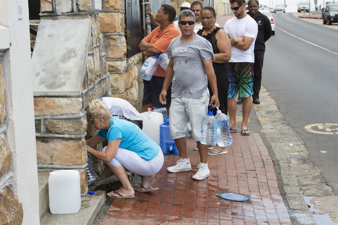 Moradores fazem fila para coletar água em uma torneira no bairro de St. James,, a cerca de 25 km do Centro da Cidade do Cabo. Foto Rodger Bosch/AFP