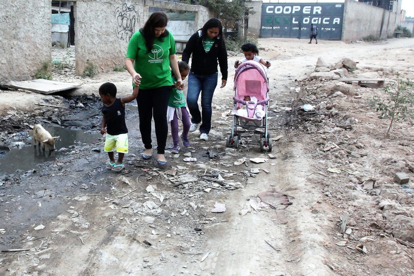 Roberta (de verde) e uma parceira da Amparanda Jardim Gramacho, com crianças atendidas pela ONG: entre lixo e porcos. Foto: Severino Silva/Divulgação