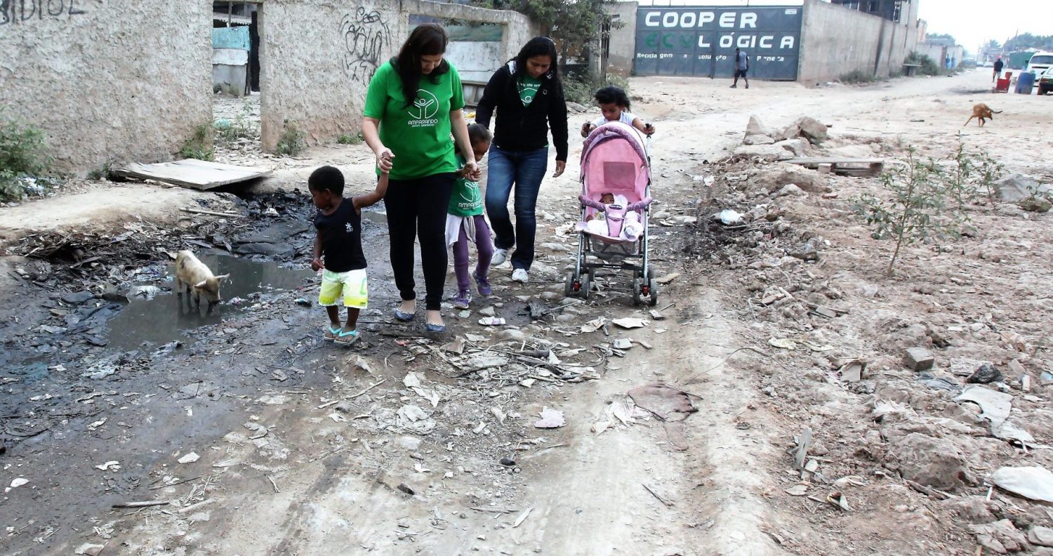 Roberta (de verde) e uma parceira da Amparanda Jardim Gramacho, com crianças atendidas pela ONG: entre lixo e porcos. Foto: Severino Silva/Divulgação