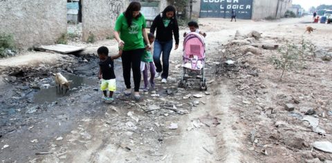 Roberta (de verde) e uma parceira da Amparanda Jardim Gramacho, com crianças atendidas pela ONG: entre lixo e porcos. Foto: Severino Silva/Divulgação