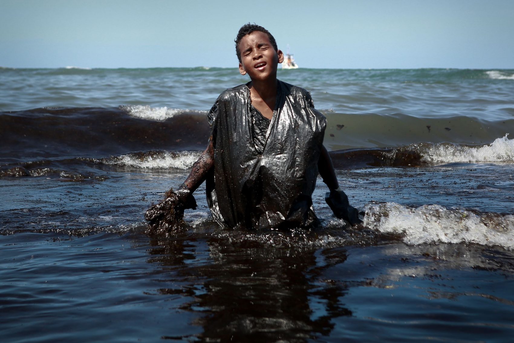 Voluntário no trabalho de limpeza das praias em Cabo de Santo Agostinho (PE), adolescente sai do mar coberto de óleo: 200 localidades atingidas em todo o Nordeste (Foto: Leo Malafaia/AFP)