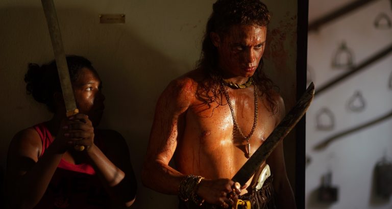 O fora da lei Lunga (Silvero Pereira) comanda, de dentro do museu, a resistência dos moradores de Bacurau, que usam as armas em exposição para mandar bala nos invasores (Foto: Victor Jucá/Divulgação)