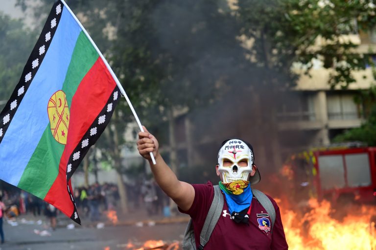 Manifestante, com uma bandeira do povo indígena Mapuche, protesta contra a política econômica do governo chileno. Foto Martin Bernetti/AFP