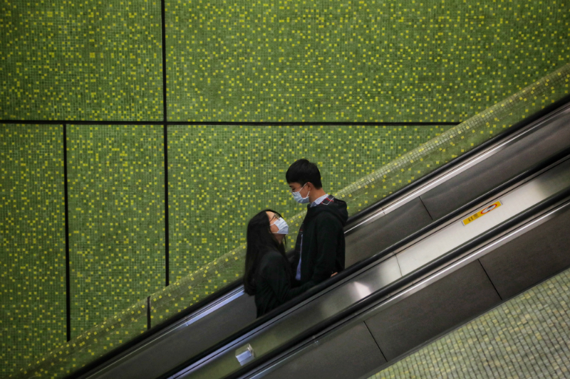Jovem casal em escada rolante em Hong King: amor em tempos de pandemia (Vivek Prakash / AFP)