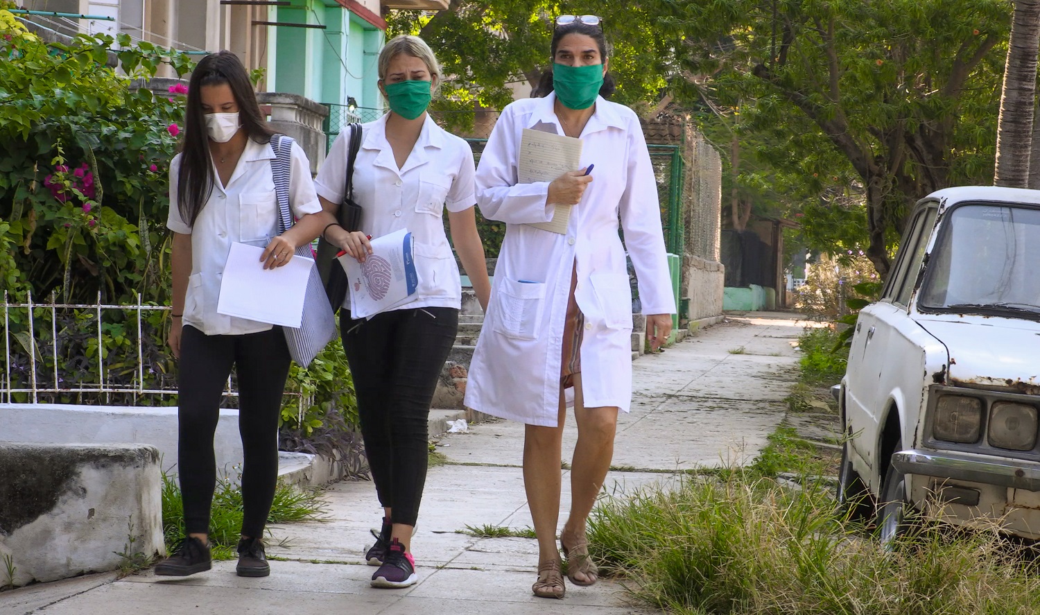 A médica cubana Liz Caballero (à direita), da policlínica El Vedado, em Havana, caminha com dois estudantes de medicina enquanto vão de porta em porta procurando possíveis casos do novo coronavírus. Foto Adalberto Roque/AFP