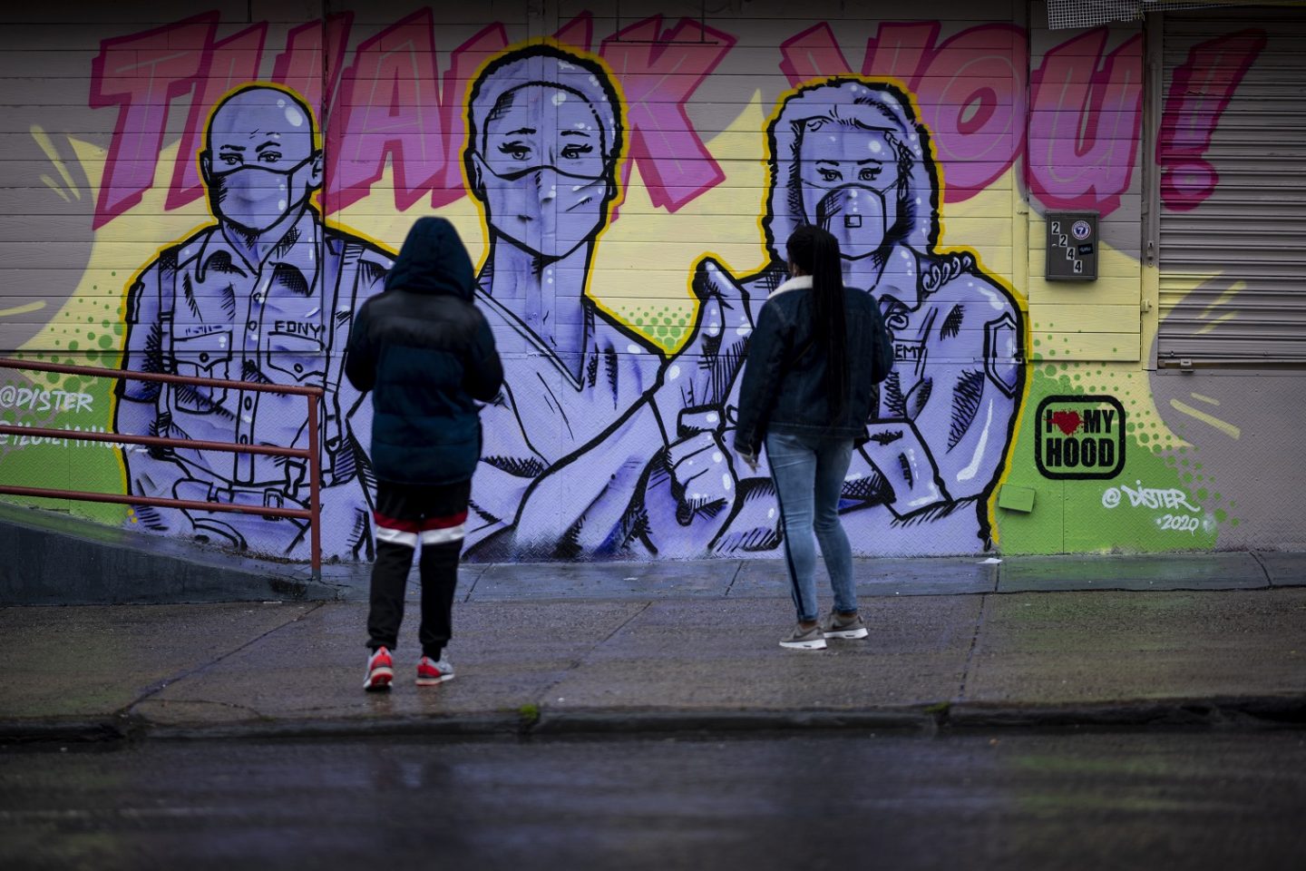 Duas mulheres no Harlem, em Nova York, observam o mural do artista @Dister, retratando socorristas com máscaras e uma mensagem de agradecimento. Foto Johannes Eisele/AFP