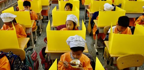 Em Taiwan, alunos almoçam em mesas com divisórias plásticas como medida preventiva para conter a disseminação da covid-19. Foto Sam Yeh/AFP