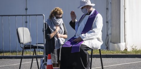 Padre usando máscara contra a covid-19 ouve a confissão de uma fiel em frente a uma igreja em Varsóvia, na Polônia. Foto Wojtek Radwanski/AFP