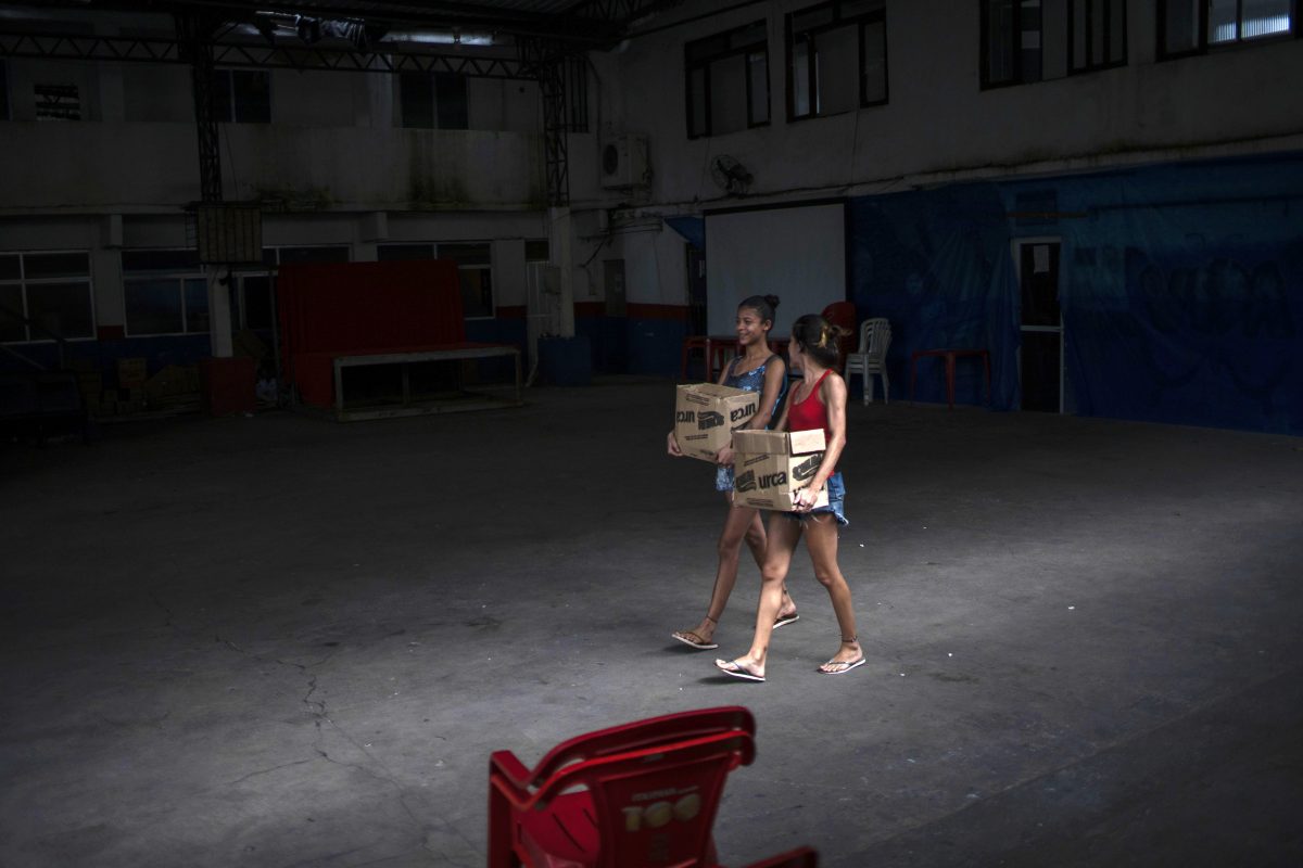 Jovens mulheres carregam caixas com donativos para enfrentar a crise causada pela pandemia na Cidade de Deus: jovens em geral e mulheres em particular terão seu futuro ameaçado pelos impactos da covid-19, alerta consultora da ActionAid (Foto: Mauro Pimentel/AFP)