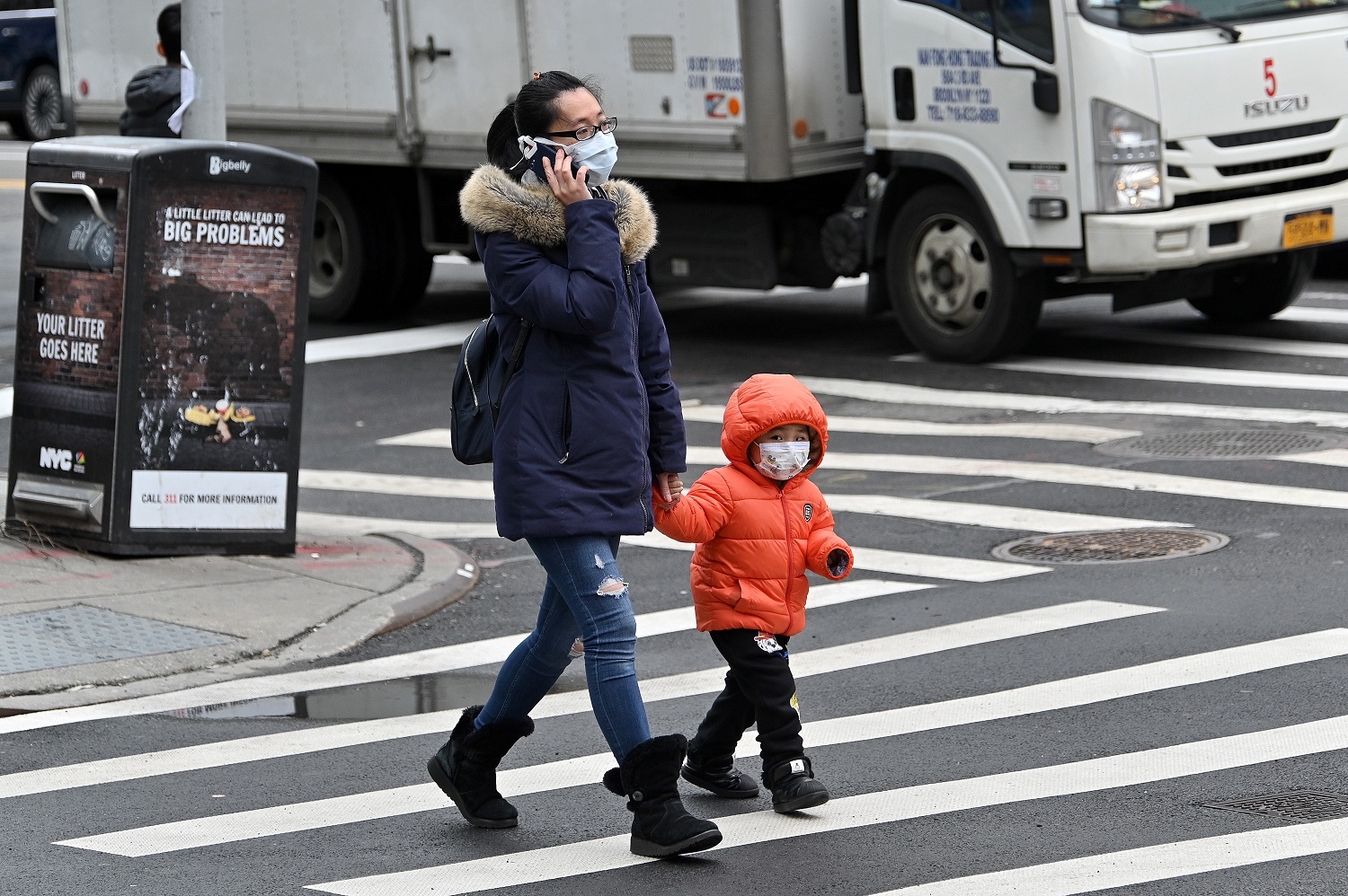 Ódio e preconceito contra asiáticos: Mulher e criança usando máscaras protetoras são vistas atravessando a rua em Chinatown, Nova York. As mulheres são as mais afetadas pelo preconceito. Foto Dia Dipasupil/Getty Images/AFP