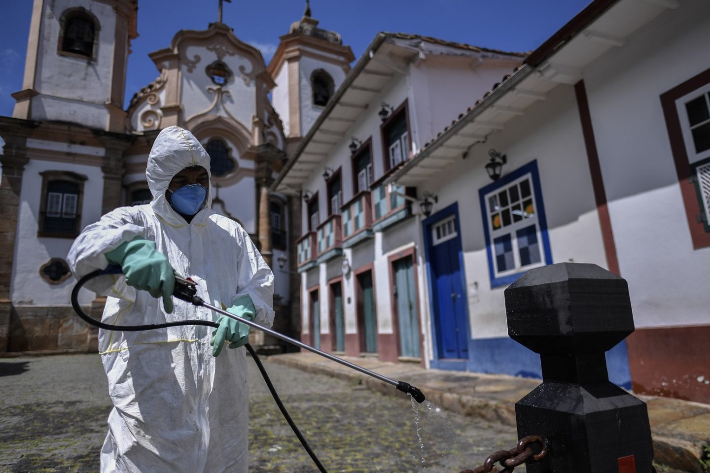 Membro de uma equipe de limpeza ajuda a desinfetar o centro histórico de Ouro Preto. Foto Douglas Magno/AFP