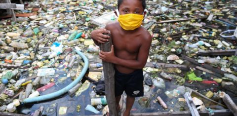 Um menino da comunidade ribeirinha de Educandos, em Manaus, brinca em meio ao lixo. Foto Michael Dantas/AFP