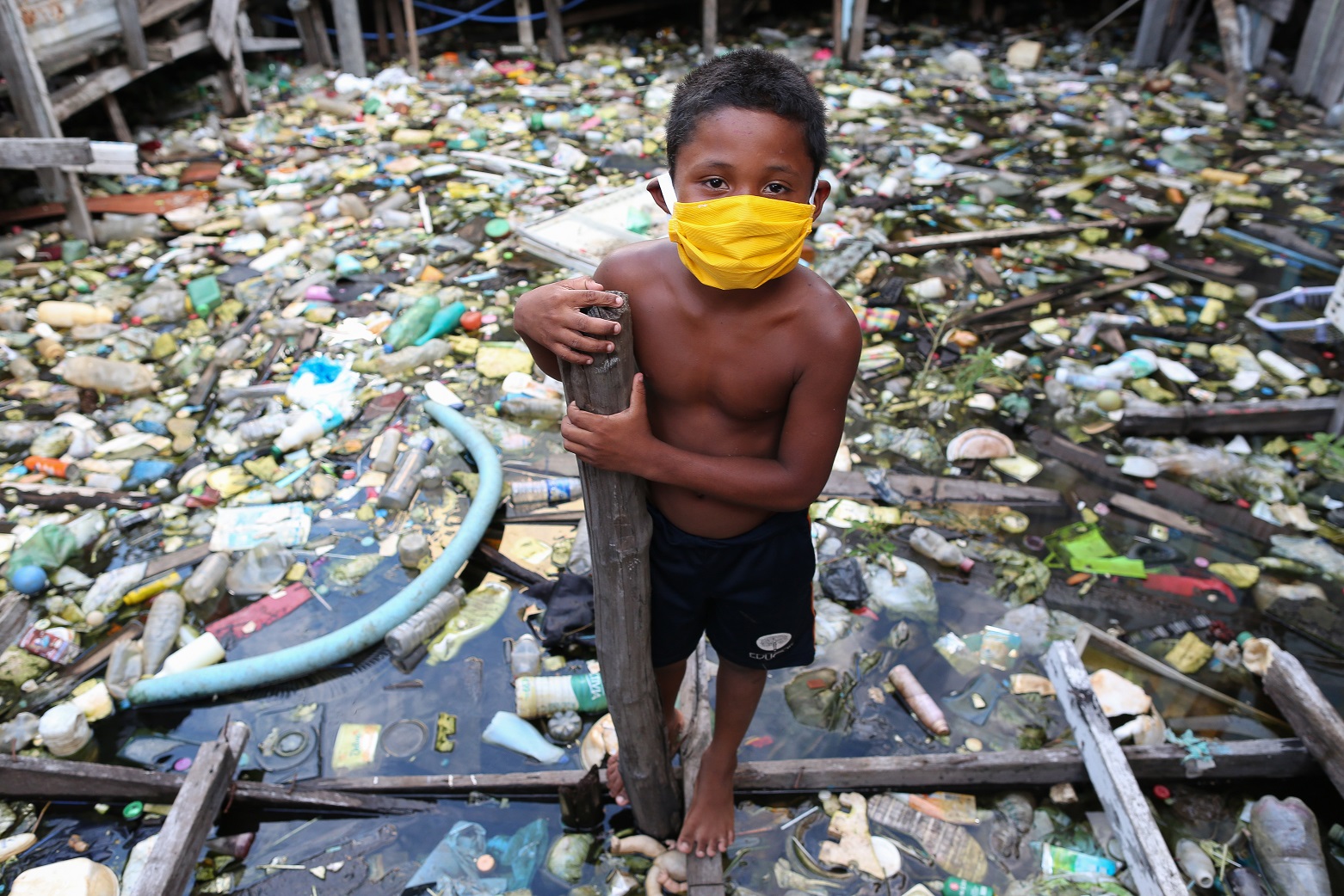 Um menino da comunidade ribeirinha de Educandos, em Manaus, brinca em meio ao lixo. Foto Michael Dantas/AFP