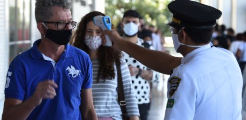 Funcionário de um shopping em Brasília checa a temperatura dos clientes no primeiro dia de funcionamento do comércio na cidade. Foto Evaristo Sá/AFP
