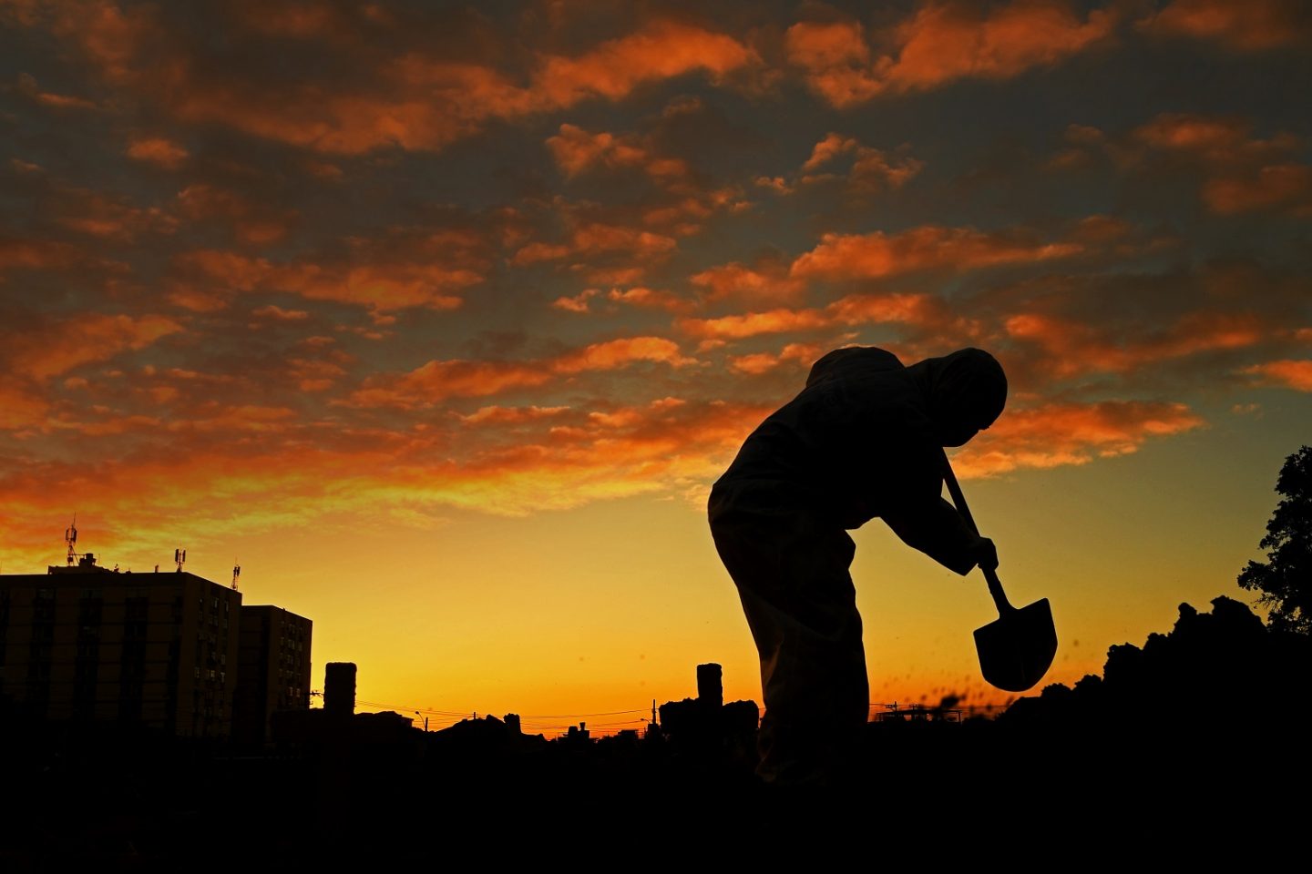 Um coveiro vestindo roupas de proteção trabalha no cemitério do Caju. Foto Carl de Souza/AFP