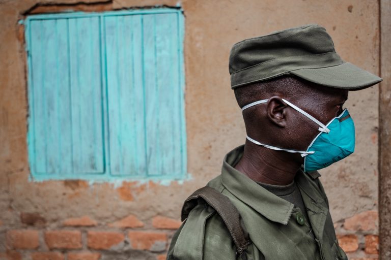 Representante da Unidade Local de Defesa (LDU), força paramilitar composta por civis, entrega farinha e feijão em alguns bairros de Uganda durante a quarentena. Foto Sumy Sadurni/AFP