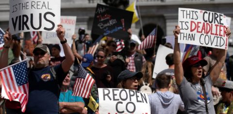 Manifestantes com cartazes - "Medo é o vírus", "A cura é mais mortal que a covid" - em Denver, no Colorado: protestos pelo fim de medidas restritivas têm semelhanças com atos no Brasil (Foto: Jason Connolly/AFP)