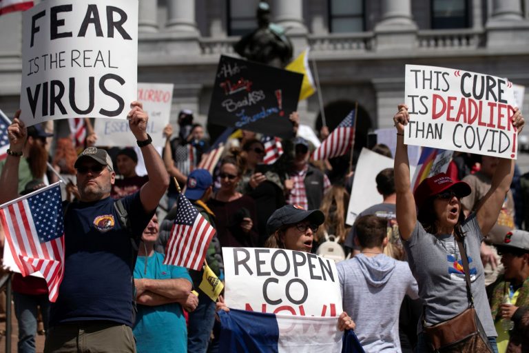 Manifestantes com cartazes - "Medo é o vírus", "A cura é mais mortal que a covid" - em Denver, no Colorado: protestos pelo fim de medidas restritivas têm semelhanças com atos no Brasil (Foto: Jason Connolly/AFP)