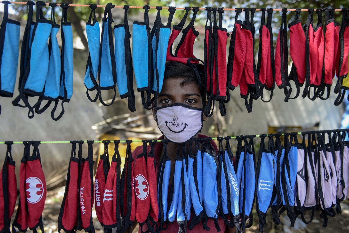 Na cidade de Hyderabad, na Índia, o jovem camelô organiza a sua barraca de máscaras contra a covid-19. foto Noah Seelam/AFP