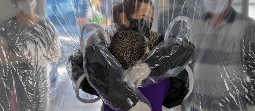 Elisabete Nagata (em cima) abraça sua cunhada Luiza Nagata, de 76 anos, através de uma cortina de plástico transparente em um lar de idosos em São Paulo. Foto Nelson Almeida/AFP