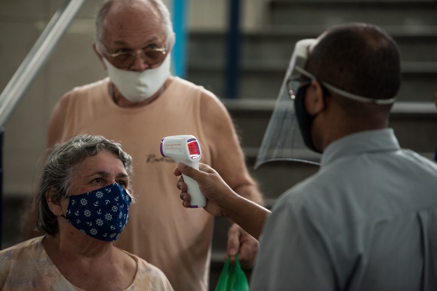 Casal de idosos tem a sua temperatura checada na entrada no Mercadão de Madureira. Foto Allan Carvalho/NurPhoto