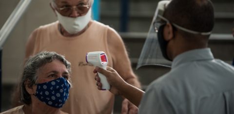Casal de idosos tem a sua temperatura checada na entrada no Mercadão de Madureira. Foto Allan Carvalho/NurPhoto