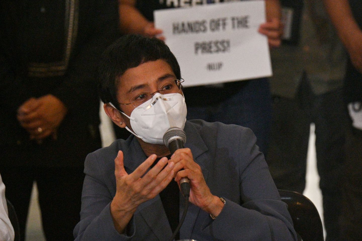 À frente de cartaz com a mensagem "Tire as mãos da imprensa", a jornalista Maria Ressa dá entrevista após ser condenada por "ciber-difamação": democracia e jornalismo sob ataque nas Filipinas (Foto: Ted Aljib/AFP)