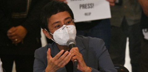 À frente de cartaz com a mensagem "Tire as mãos da imprensa", a jornalista Maria Ressa dá entrevista após ser condenada por "ciber-difamação": democracia e jornalismo sob ataque nas Filipinas (Foto: Ted Aljib/AFP)