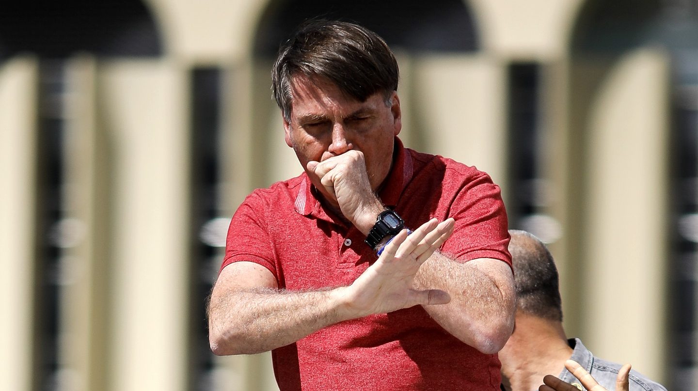 Em imagem feito no dia 19 de abril, em Brasília, o presidente Bolsonaro tosse enquanto fala depois de se juntar a seus apoiadores que estavam participando de uma carreata para protestar contra medidas de quarentena e distanciamento social para combater o novo coronavírus. Foto Sérgio Lima/AFP
