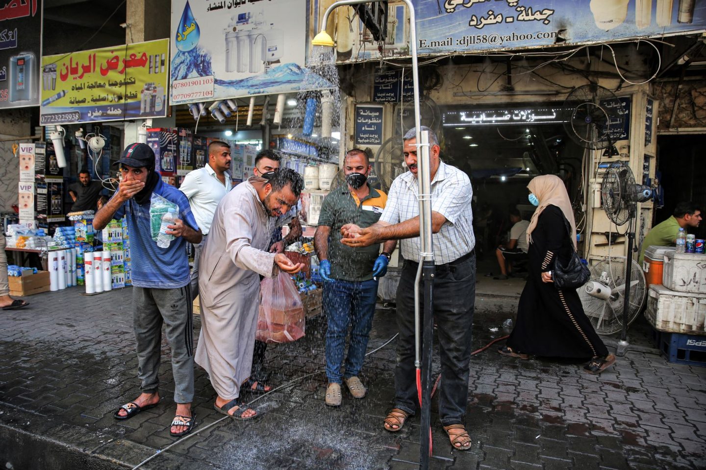 Em Bagdá, no Iraque, homens se refrescam em chuveiro instalado na rua para enfrentar temperatura que passou dos 50 graus em julho: segunda maior temperatura no mês de julho na história (Foto: Ahmad Al-Rubaye/AFP)