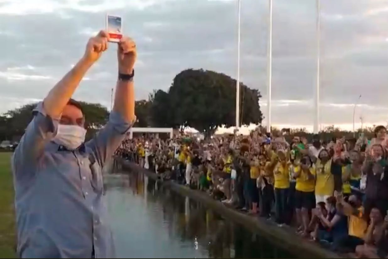O presidente Jair Bolsonaro mostra uma caixa de hidroxicloroquina para os apoiadores na frente do Palácio da Alvorada. Foto AFP
