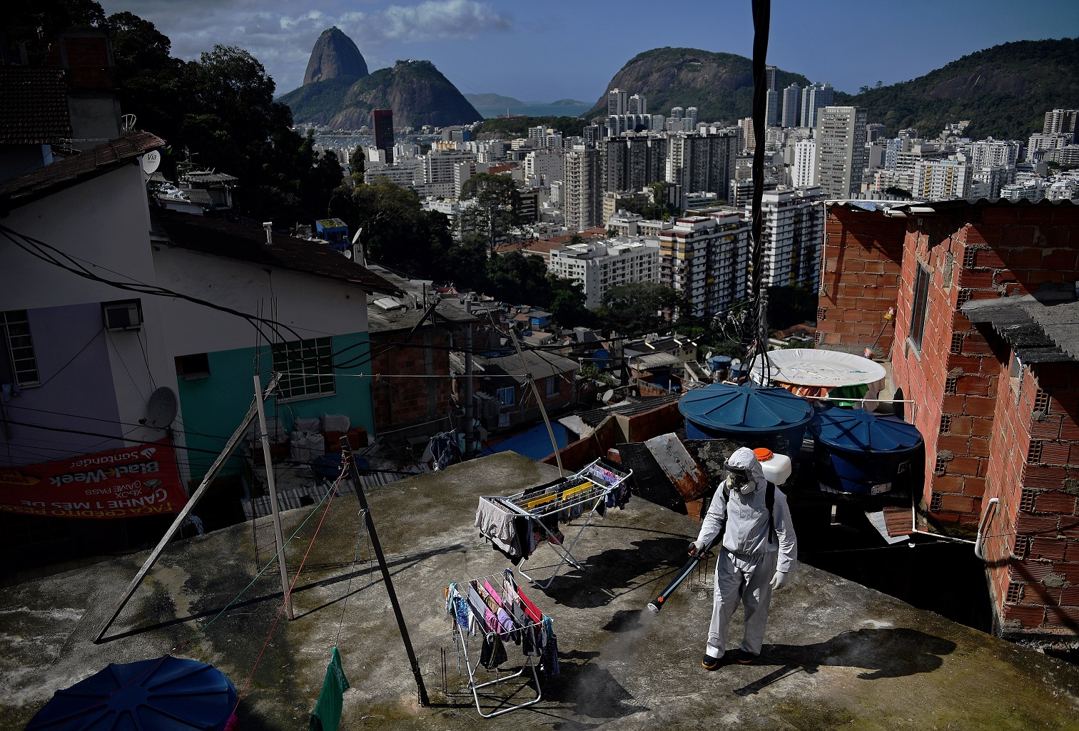 Voluntário desinfeta uma área de cobertura dentro da Favela de Santa Marta, no Rio de Janeiro. Foto Carl de Souza/AFP