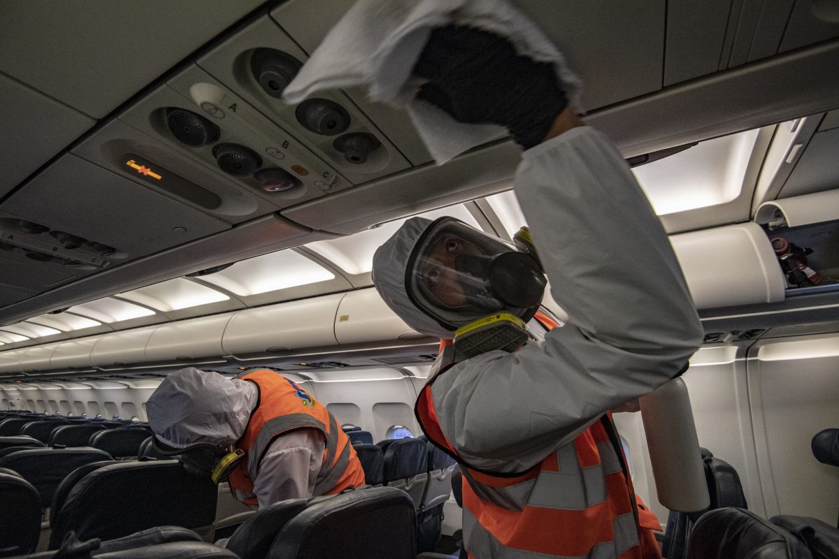 Trabalhadores com macacões de biossegurança desinfetam um avião, no hangar da LATAM, no aeroporto internacional El Dorado, em Bogotá. Foto Juan Barreto/AFP