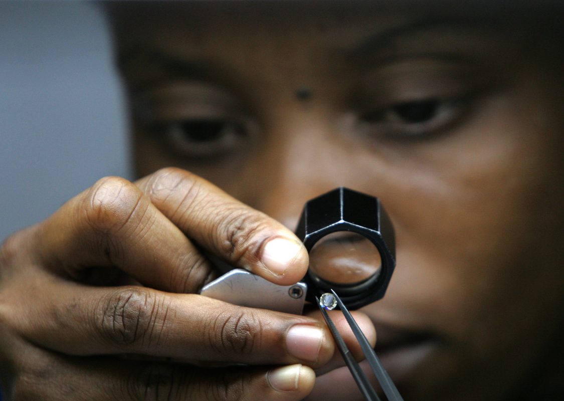 Trabalhadora examina diamante na DTCB, joint venture da mineradora De Beers com o governo de Botsuana. Foto de Alexander Joe (AFP)
