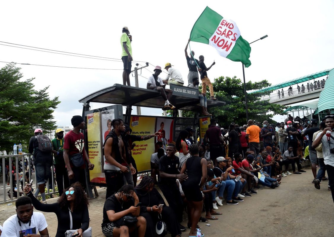 Manifestante com bandeira da Nigéria e a exigência de fim de esquadrão acusado de violência: hashtag #EmdSARS mobilizou nigerianos e espalhou protesto por outros países (Foto: Pius Utomi EKpei / AFP)